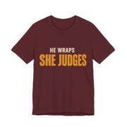 He Wraps. She Judges Shirt - Bold - Funny Christmas Tee in Maroon