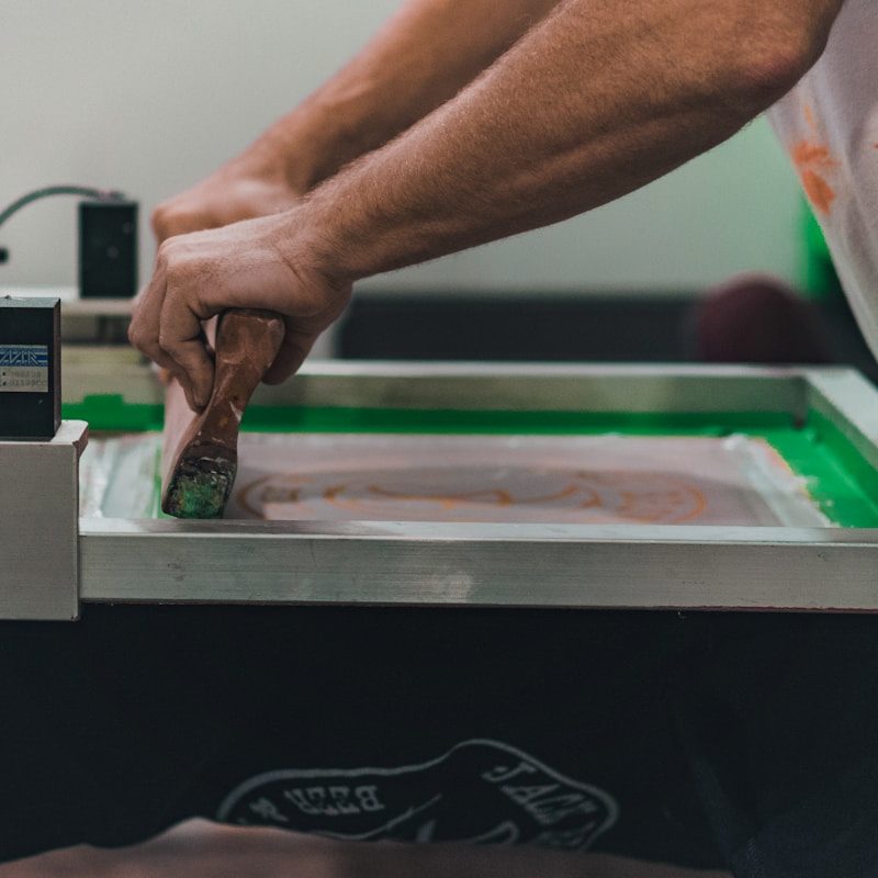 Hands screen printing a custom design onto a garment